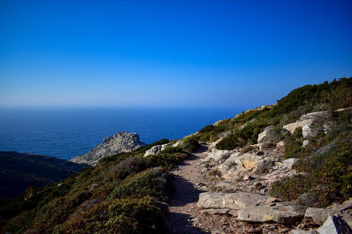 dirt path with bushes and view of the aegean sea and a castle
