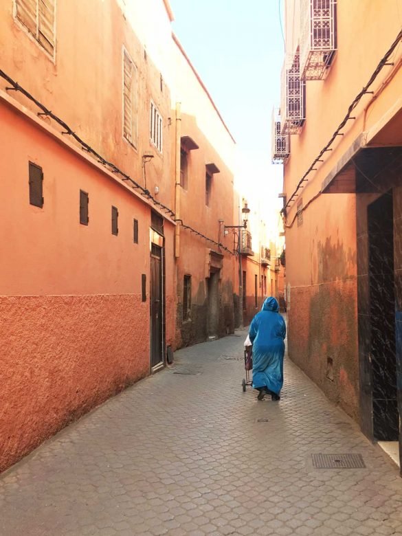 narrow street at Medina in Marrakech with woman in blue clothes walking