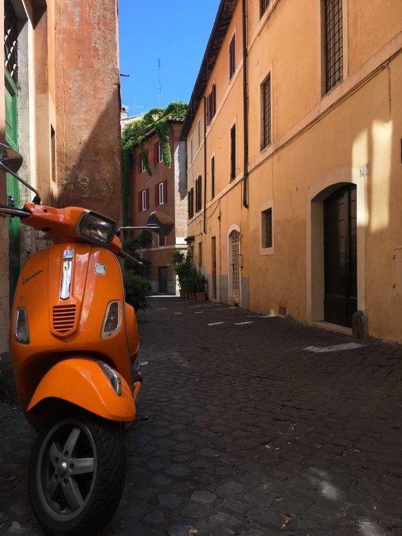 orange vespa in tiber island narrow street at rome