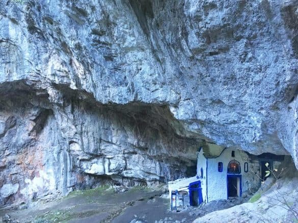 blue and white church without roof inside a cave