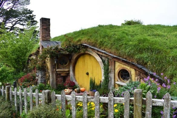 Hobbiton – New Zealand a yellow door at a hobbit house with a garden