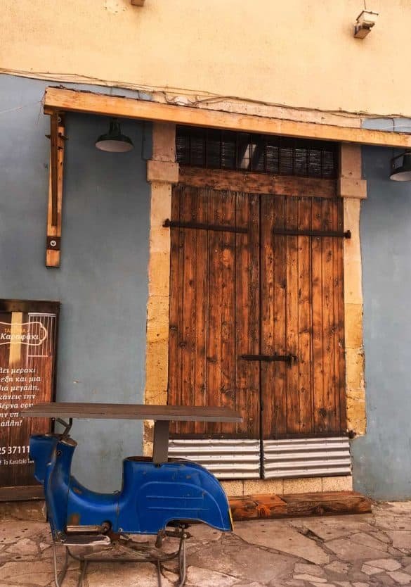 Vintage vs Modern – Limassol, Cyprus a vintage brown door and blue motorbike as a table in a cafe