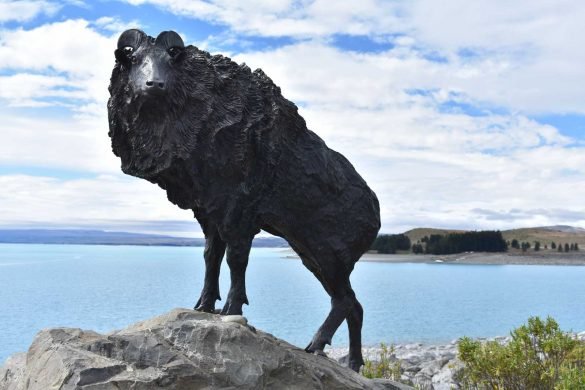 a bronze statue of tahr animal in front of a lake