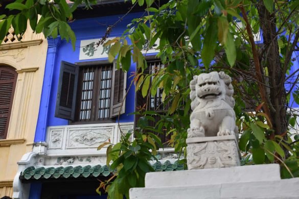 statue of a small asian dragon in front of a blue house